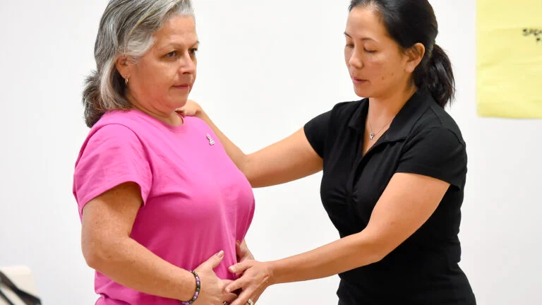 one woman shows another woman a breathing exercise