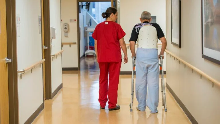 nurse helps a patient use a walker